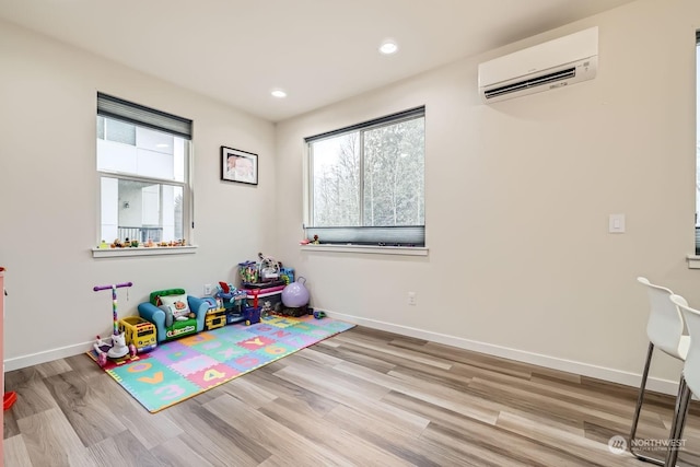 playroom with a wall unit AC and light wood-type flooring