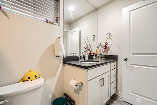 bathroom with vanity, toilet, and hardwood / wood-style floors