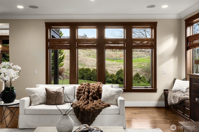 living room featuring baseboards, ornamental molding, wood finished floors, and recessed lighting