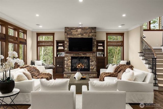 living room featuring crown molding, wood finished floors, a wealth of natural light, and a stone fireplace