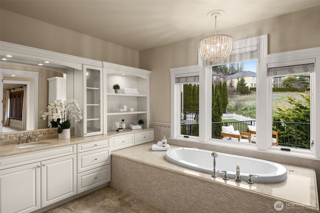 full bathroom featuring a bath, vanity, and an inviting chandelier