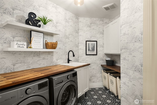 laundry room featuring a sink, visible vents, cabinet space, washer and clothes dryer, and wallpapered walls