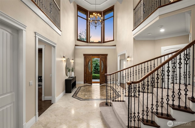 foyer entrance with a chandelier, a high ceiling, stairs, and baseboards