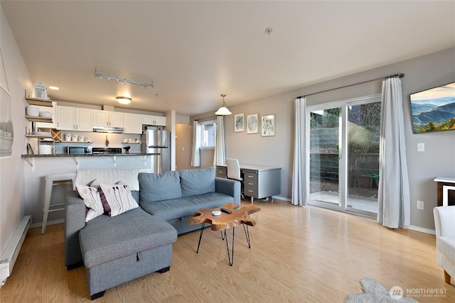 living room featuring rail lighting, a baseboard heating unit, and light wood-type flooring