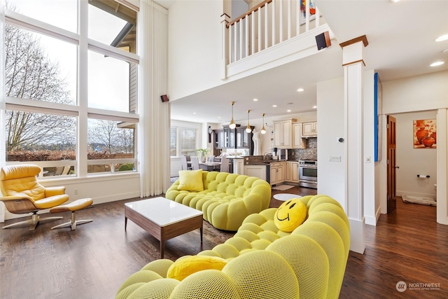 living room featuring dark wood-type flooring, a high ceiling, and ornate columns