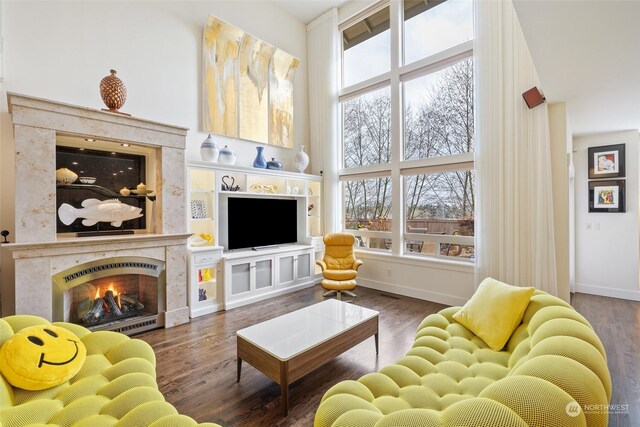 living room featuring a premium fireplace, dark hardwood / wood-style flooring, and a high ceiling