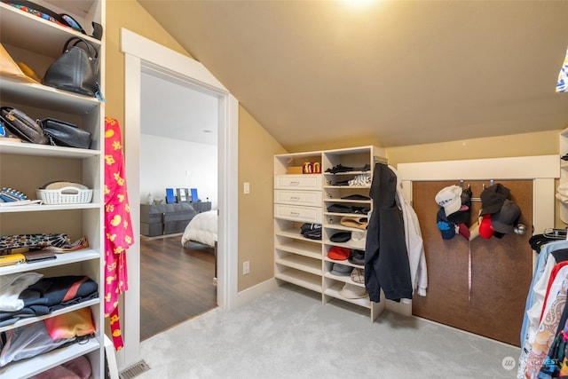 walk in closet featuring lofted ceiling and light colored carpet