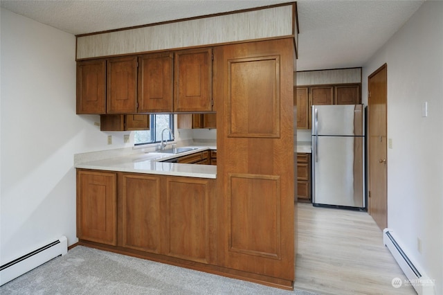 kitchen featuring sink, a textured ceiling, stainless steel fridge, and baseboard heating