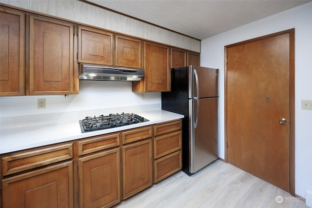 kitchen featuring appliances with stainless steel finishes, light hardwood / wood-style floors, and a textured ceiling