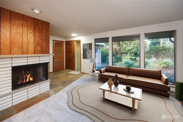 living room featuring a brick fireplace, a textured ceiling, and a baseboard heating unit