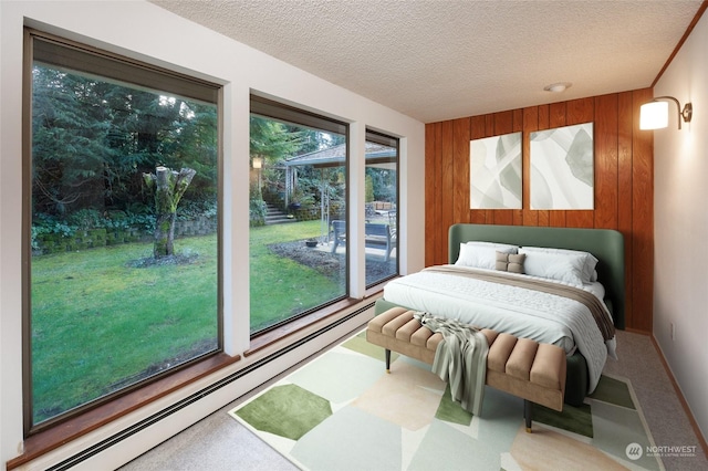 bedroom featuring carpet flooring, a baseboard radiator, wooden walls, and a textured ceiling