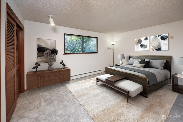 bedroom with light colored carpet, a closet, a textured ceiling, and baseboard heating