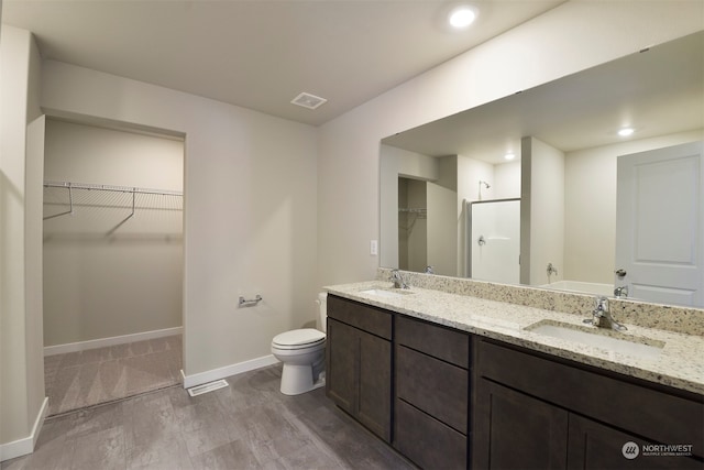 bathroom featuring a shower with door, vanity, hardwood / wood-style flooring, and toilet