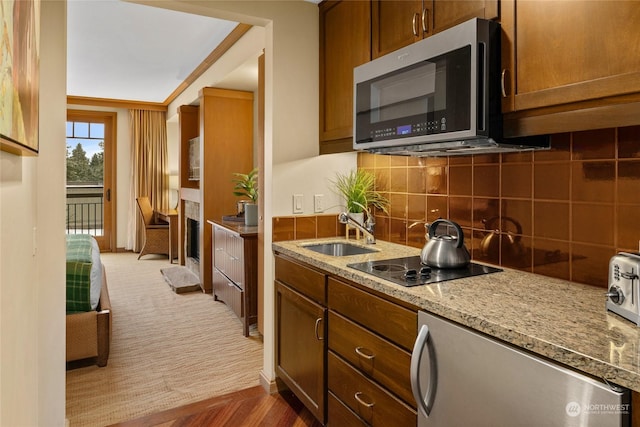 kitchen featuring sink, stainless steel appliances, carpet flooring, light stone countertops, and decorative backsplash