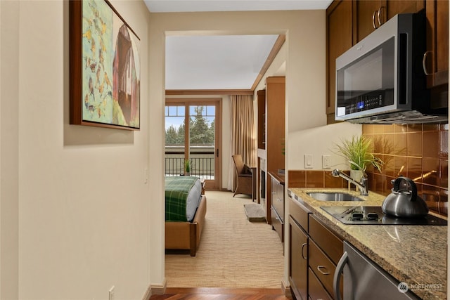 kitchen featuring tasteful backsplash, stainless steel appliances, stone countertops, and sink