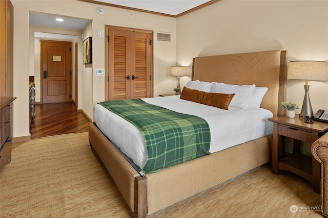 bedroom with crown molding, wood-type flooring, and a closet