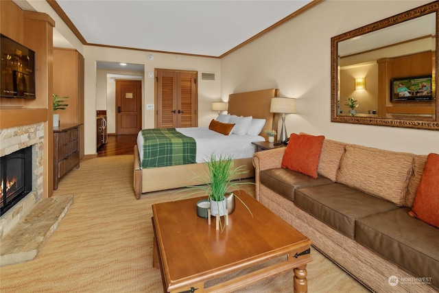 bedroom featuring crown molding, light wood-type flooring, a fireplace, and a closet