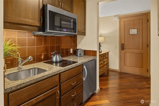 kitchen featuring sink, decorative backsplash, light stone countertops, and dark hardwood / wood-style floors