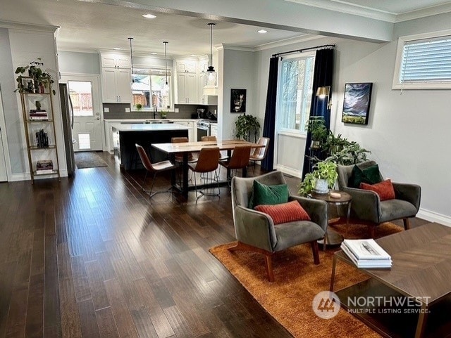 dining area featuring ornamental molding, dark wood-type flooring, and sink