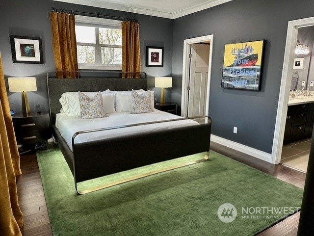 bedroom with connected bathroom, crown molding, and dark wood-type flooring