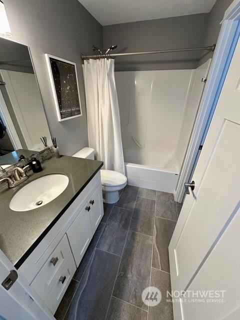 full bathroom with vanity, shower / bath combo, and toilet