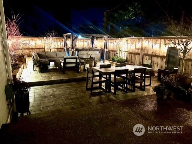 patio at night featuring an outdoor living space and a hot tub