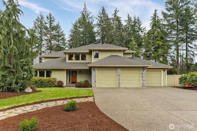 view of front of house featuring a front lawn, fence, roof with shingles, a garage, and driveway