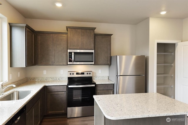 kitchen with light stone counters, appliances with stainless steel finishes, dark wood-type flooring, and sink