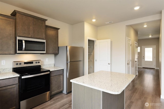 kitchen with stainless steel appliances, dark brown cabinets, and a center island