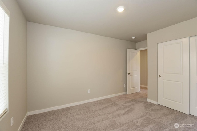 unfurnished bedroom with light carpet and a closet