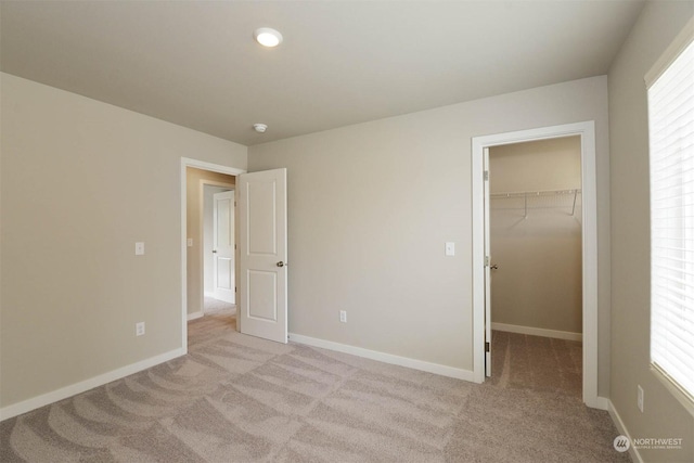 unfurnished bedroom featuring a spacious closet, light carpet, and a closet