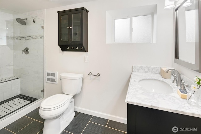 bathroom featuring baseboards, a shower stall, toilet, and vanity