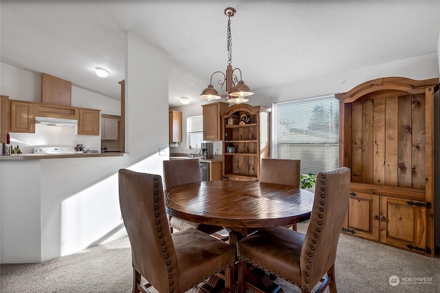 dining space with a chandelier, vaulted ceiling, and light carpet