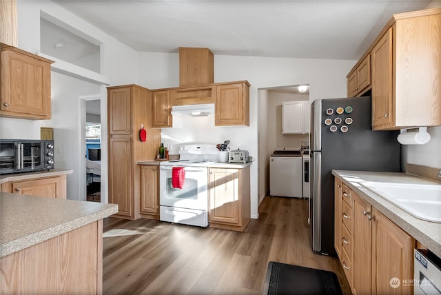 kitchen with lofted ceiling, sink, stainless steel refrigerator, electric range, and washing machine and dryer