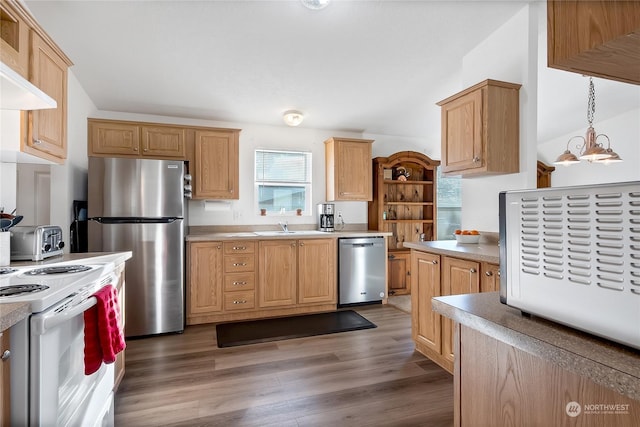 kitchen with dark wood-type flooring, hanging light fixtures, stainless steel appliances, wall chimney exhaust hood, and light brown cabinets