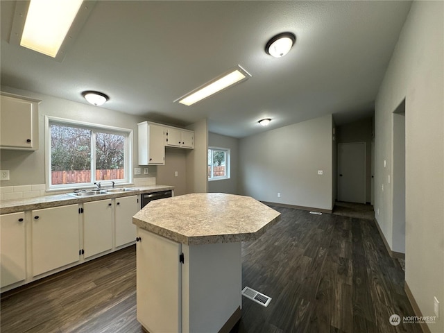 kitchen featuring a kitchen island, sink, dishwashing machine, white cabinets, and plenty of natural light