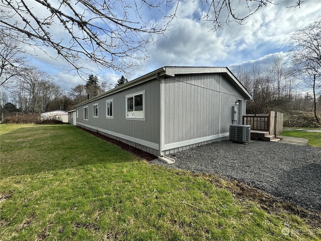 view of side of property with central AC unit and a lawn