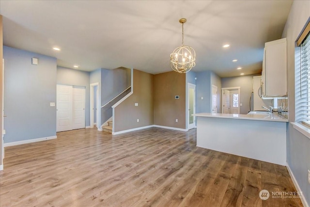 kitchen featuring pendant lighting, kitchen peninsula, light hardwood / wood-style flooring, and white cabinets