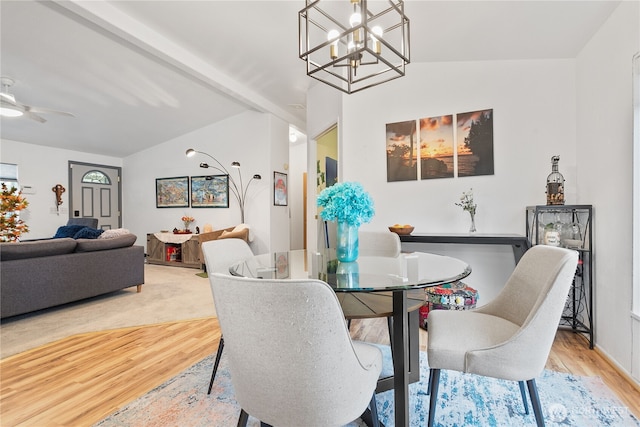 dining room with ceiling fan with notable chandelier, light hardwood / wood-style flooring, and lofted ceiling with beams