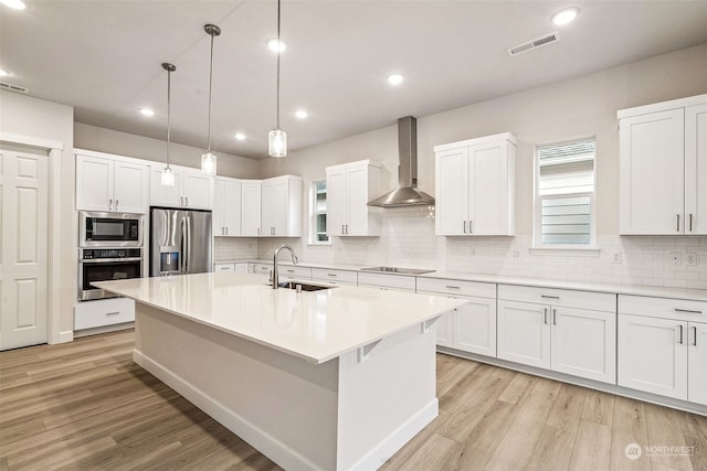 kitchen featuring stainless steel appliances, white cabinetry, sink, and wall chimney exhaust hood