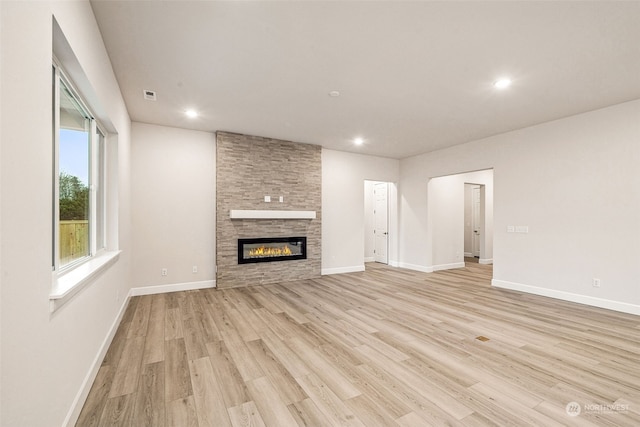 unfurnished living room with a stone fireplace and light hardwood / wood-style flooring