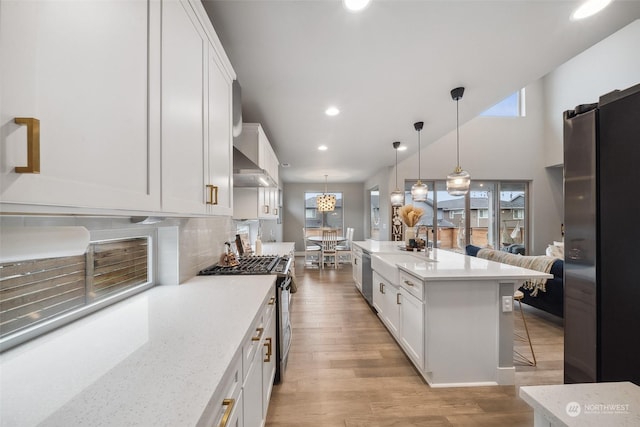 kitchen with a breakfast bar, light stone counters, hanging light fixtures, stainless steel appliances, and white cabinets