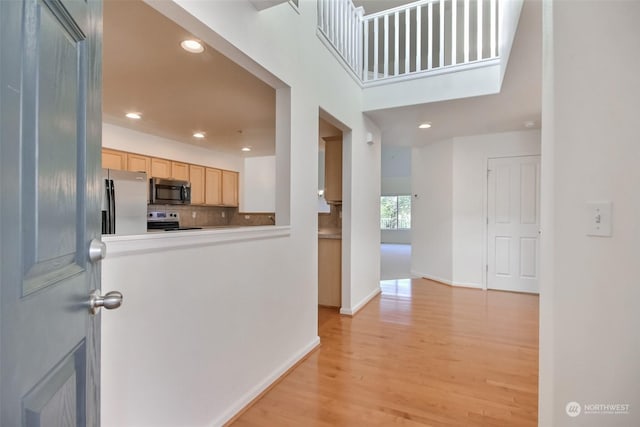 kitchen featuring decorative backsplash, stainless steel appliances, light hardwood / wood-style floors, and light brown cabinets