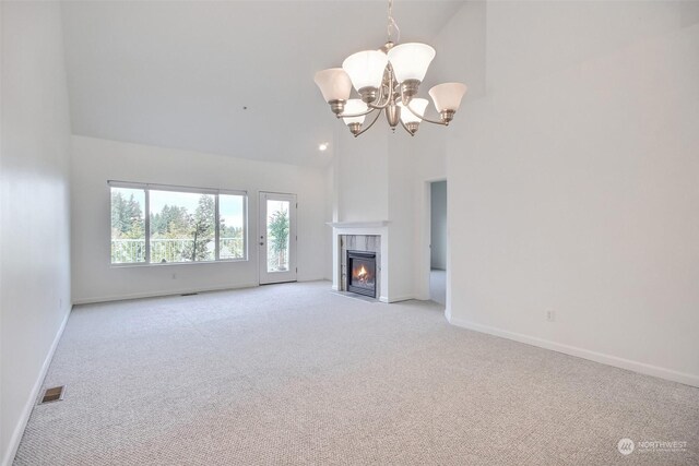 unfurnished living room featuring a tile fireplace, a chandelier, high vaulted ceiling, and light carpet