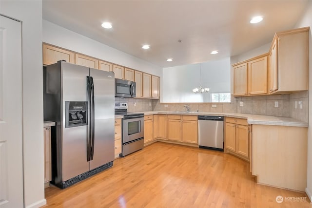 kitchen with light brown cabinetry, sink, a notable chandelier, stainless steel appliances, and light hardwood / wood-style floors