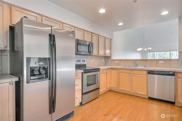 kitchen featuring appliances with stainless steel finishes, light brown cabinetry, sink, and hanging light fixtures