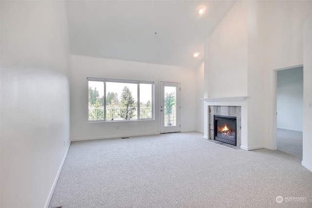 unfurnished living room featuring a tile fireplace, light carpet, and high vaulted ceiling