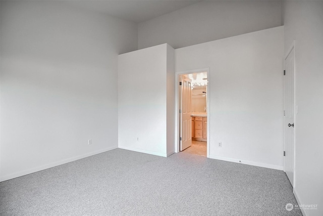 unfurnished bedroom featuring light carpet and ensuite bath