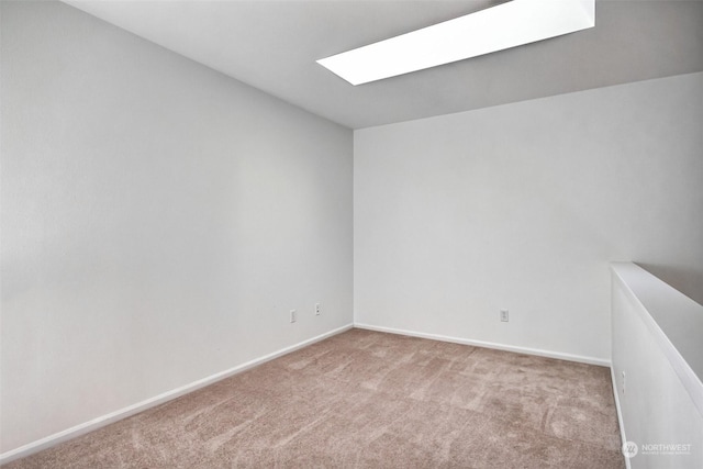 carpeted spare room featuring a skylight