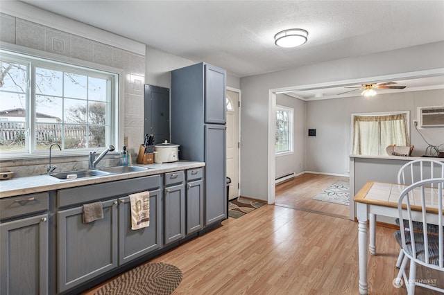 kitchen featuring sink, gray cabinets, ceiling fan, a baseboard radiator, and light wood-type flooring